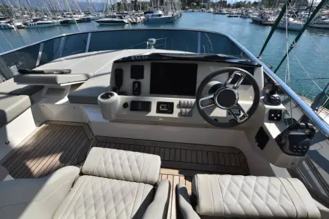 Absolute 50 Fly: flybridge helm with twin quilted cream seats, wheel and navigation display overlooking the marina