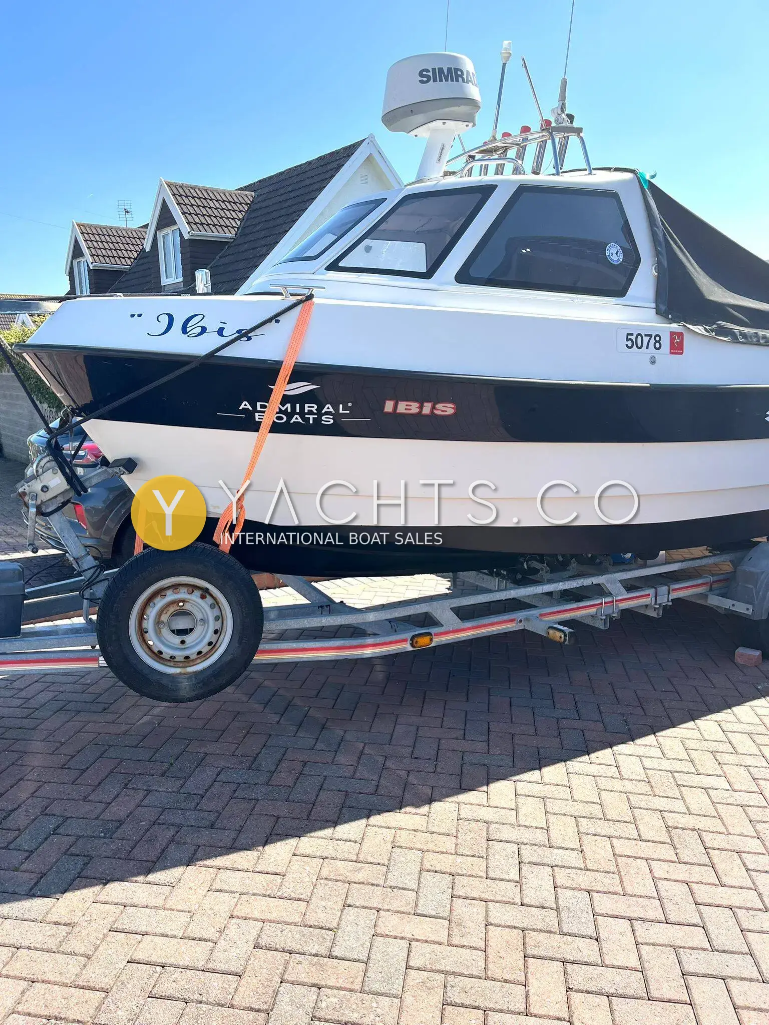 Admiral Shipyard Pro Fish 560: starboard bow view of the white wheelhouse hull on her trailer, strapped down on a paved drive
