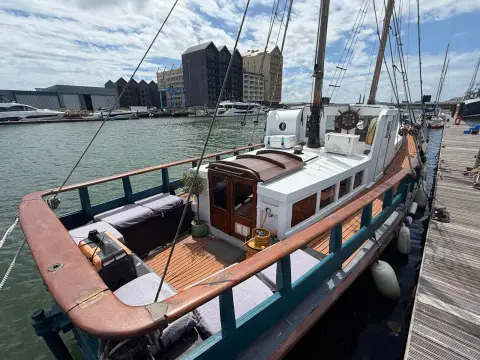 Admiralty Ketch: aft deck with teak decking, cushioned seating along varnished rails and wheelhouse doors