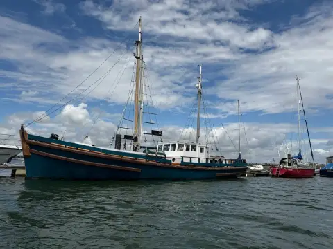 Admiralty Ketch: blue hull and white superstructure seen from the water, other yachts moored behind
