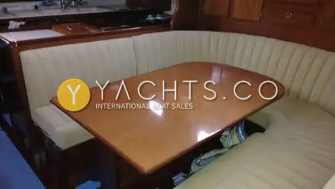 Amel Super Maramu 2000: saloon dinner table in varnished wood with cream curved upholstered seating