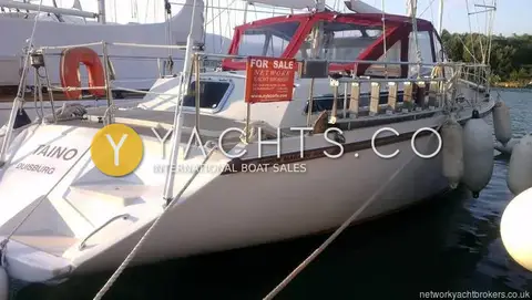Amel Super Maramu 2000: stern quarter with For Sale sign on the guardrail and red canopy over the centre cockpit
