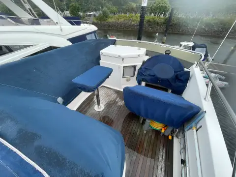 Aquastar 48 S: flybridge seating under navy covers with teak sole and pedestal stool