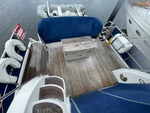 Aquastar 48 S: teak-decked cockpit with folding table, covered seating and lifebuoys on the rails