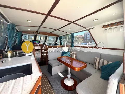 Aquastar Oceanranger 33: saloon with grey upholstered seating, wooden table and galley counter to the left
