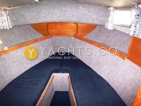 Aquastar Pacesetter 27 Boat For Sale: forward cabin V-berth with blue cushions, teak trim and grey carpeted lining