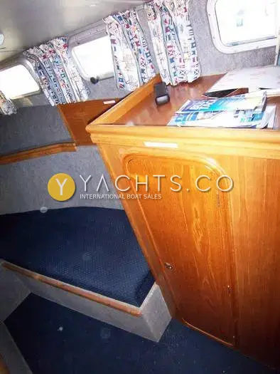 Aquastar Pacesetter 27 Boat For Sale: forward cabin berth beside a teak locker with chart storage on top