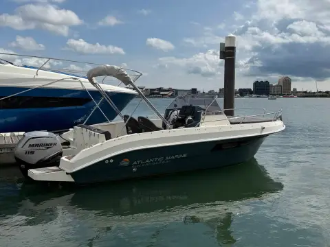 Atlantic Sun Cruiser 630: starboard profile afloat in the marina showing stainless bimini frame and outboard