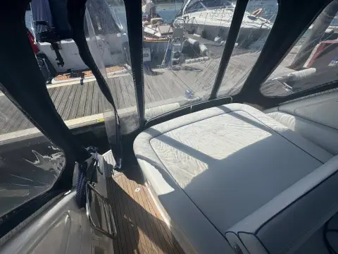 Bavaria 27 Sport: aft sunpad seen through the camper cover clear panels, teak cockpit floor below