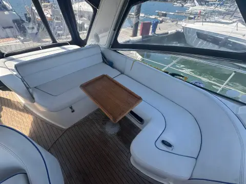 Bavaria 27 Sport: cockpit U-shaped cream seating around a teak table, enclosed by camper cover