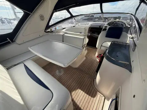 Bavaria 29 Sport: cockpit with white vinyl seating, folding table and synthetic teak decking under canvas