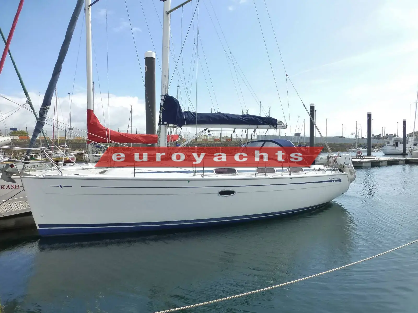 Bavaria 33 Cruiser: white hull with blue boot stripe moored in marina, sprayhood and stack pack fitted