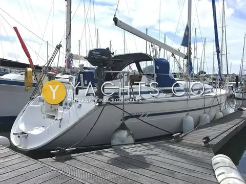 Bavaria 36: port side alongside pontoon with blue hull stripe, sprayhood and outboard on pushpit