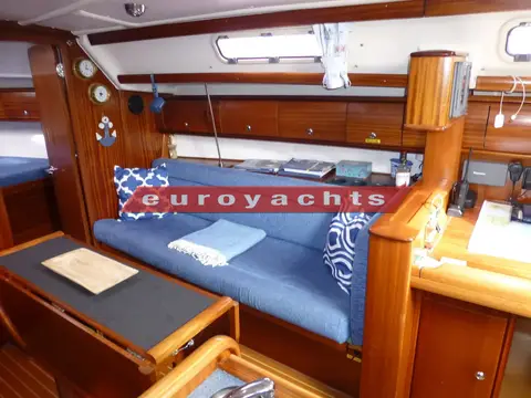 Bavaria 36: starboard saloon settee in blue with cushions beside the chart table