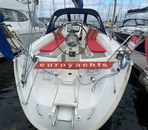 Bavaria 37: cockpit from astern with wheel, red cushions, teak seats and open transom