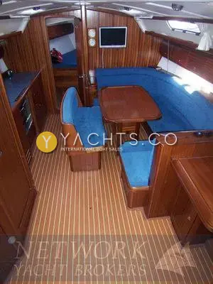 Bavaria 38: saloon looking forward, blue upholstered dinette, wall-mounted LCD TV and teak-effect sole