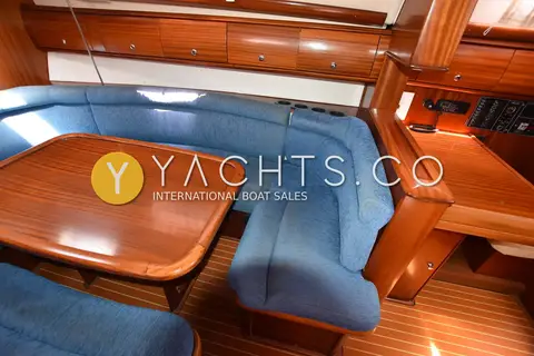 Bavaria 38: saloon U-shaped blue settee around varnished table, chart table to the right