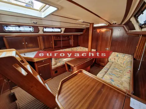 Bavaria 38 Ocean: saloon looking forward past the companionway steps, mahogany joinery and patterned upholstery