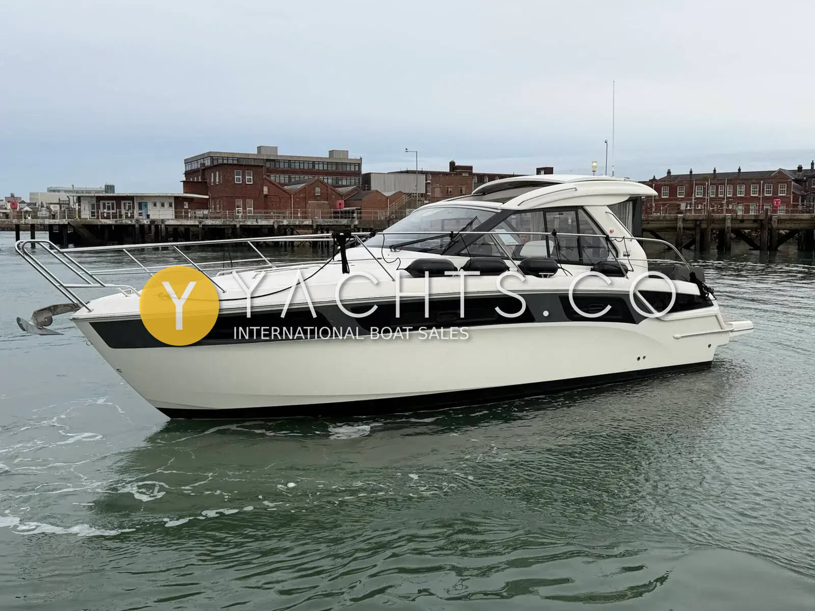 Bavaria S36: starboard side of the white hull with dark hull windows, moored in harbour
