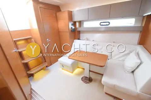 Bavaria Sport 400 HT: saloon with cream leather L-shaped settee, wooden table and lit companionway steps