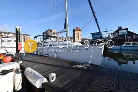 Bavaria Yachts Bavaria 30 Cruiser: hull alongside a wooden pontoon with fenders out and a brokerage sale sign on the pulpit