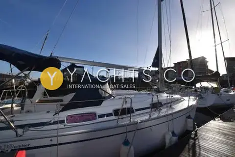 Bavaria Yachts Bavaria 30 Cruiser: starboard side deck and blue sprayhood seen from the stern, with the sun low over the marina