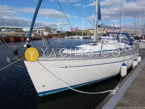 Bavaria Yachts Bavaria 34: bow view of white hull with blue stripes moored in a marina with buildings behind