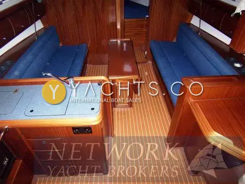 Bavaria Yachts Bavaria 36 Cruiser: saloon looking forward past galley worktop to blue settees, wooden table and teak-effect sole