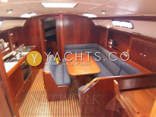 Bavaria Yachts Bavaria 40: saloon with blue U-shaped seating around a varnished table, galley to port and teak-and-holly sole