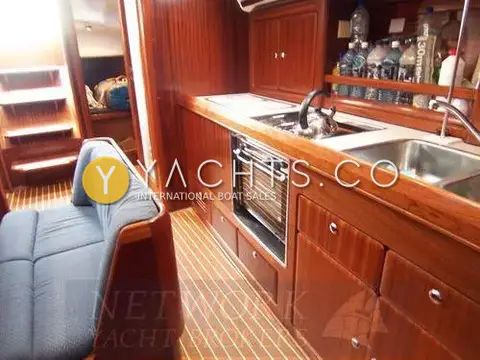 Bavaria Yachts Bavaria 40: linear galley with oven, hob, double sink and mahogany drawers beside blue saloon seating