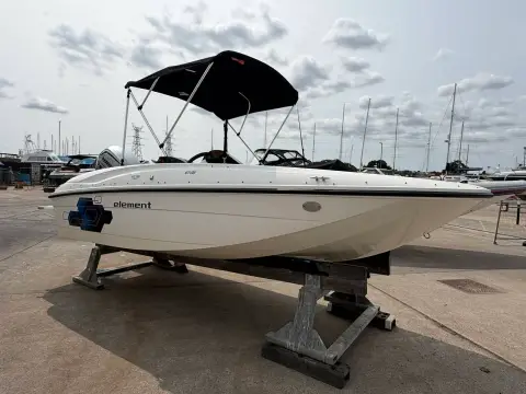 Bayliner 160 Element: port bow quarter view showing hull and black bimini top on hardstanding