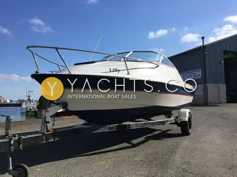 Bayliner 192 Cuddy: bow quarter view on trailer beside a marine services shed under blue sky