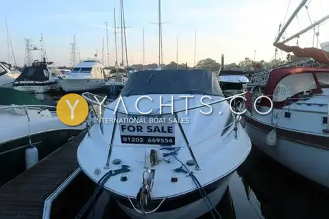 Bayliner 245: bow-on view in a marina berth with stainless pulpit, anchor and a for sale board