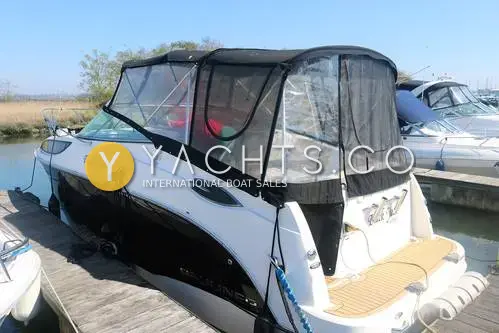 Bayliner 255: starboard quarter view of the white and black hull with full canopy, moored at a pontoon