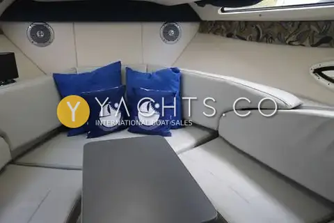 Bayliner 255: forward saloon U-shaped seating in grey with blue cushions around a dinette table