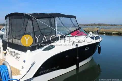 Bayliner 255: port side view of the hull with canopy up, fenders out and reed beds behind