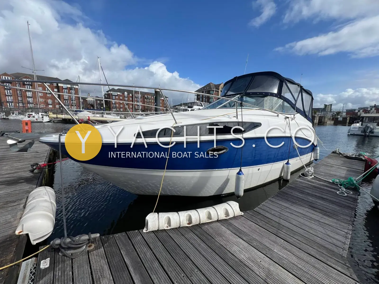 Bayliner 265: blue and white hull with canopy fitted, moored alongside a wooden pontoon in a marina
