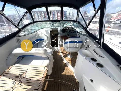 Bayliner 265: cockpit looking forward to the helm and windscreen, with blue-trimmed upholstery
