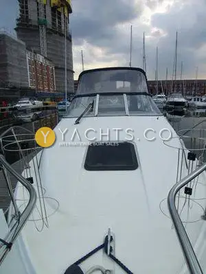 Bayliner 2655 Ciera: foredeck with hatch, stainless rails and windscreen, moored in a marina beside a building site