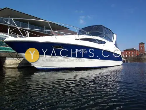 Bayliner 285: navy and white hull with bow rails and canopy, moored in a sunny marina basin