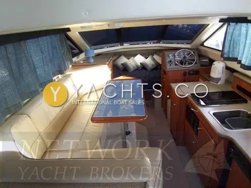 Bayliner 288 Classic: saloon looking forward past cream L-shaped dinette and table to lower helm and galley