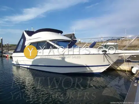 Bayliner 288 Classic: starboard side of the white flybridge hull with blue canvas, moored in marina