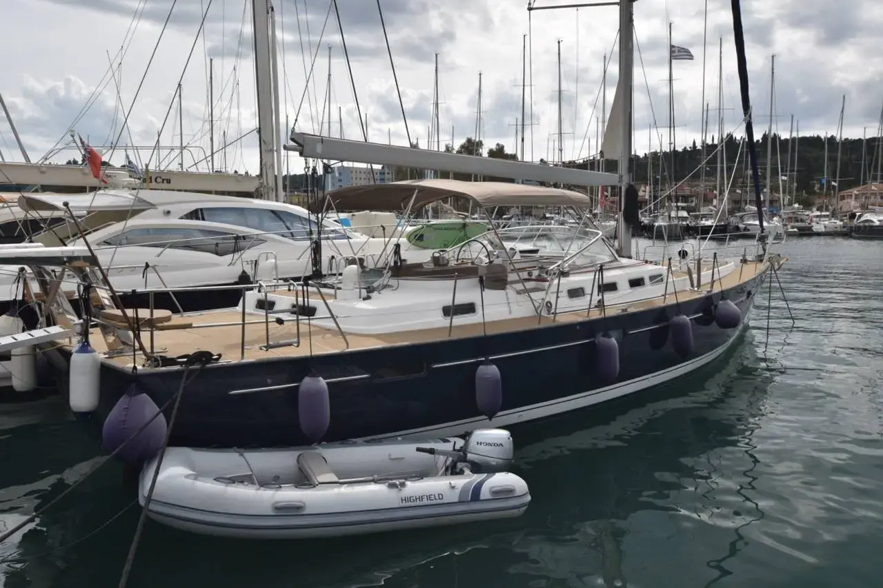 Beneteau 57: dark blue hull moored stern-to in a marina, grey RIB tender alongside