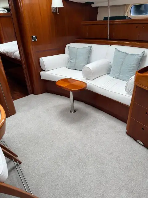 Beneteau 57: white saloon settee with small pedestal table against warm wood panelling