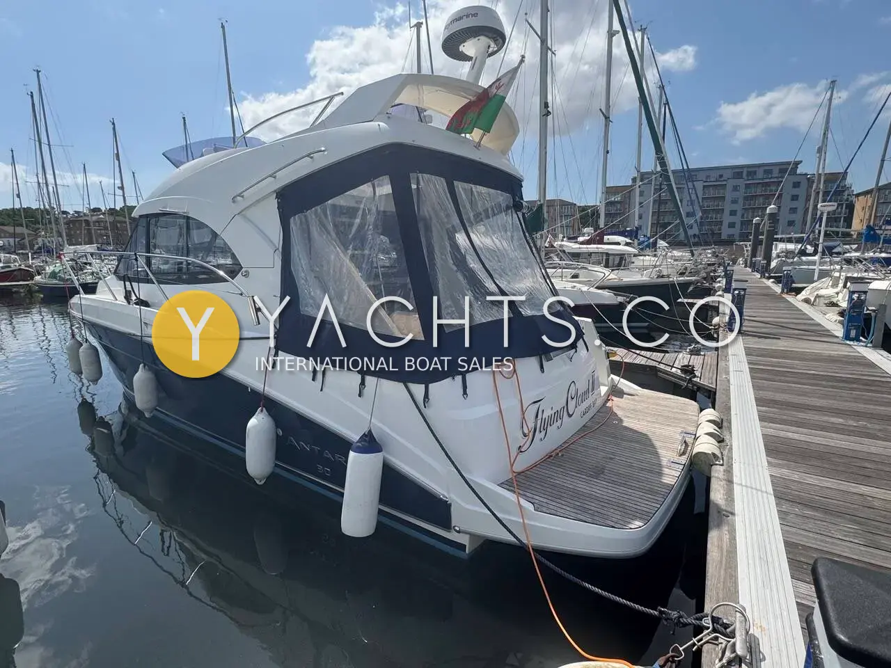 Beneteau Antares 30: blue-hulled flybridge motor boat berthed at a marina pontoon with cockpit enclosure fitted