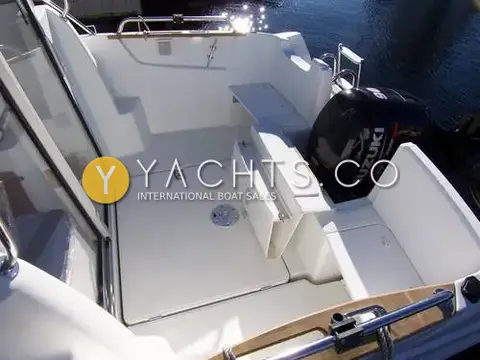 Beneteau Antares 5.80: aft cockpit with white moulded floor hatch, folding aft seat and black Suzuki outboard behind