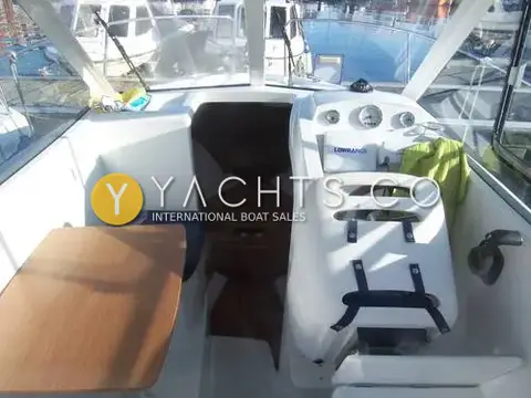 Beneteau Antares 5.80: wheelhouse interior with wooden table to port, helm seat and dash, and steps down to the cabin
