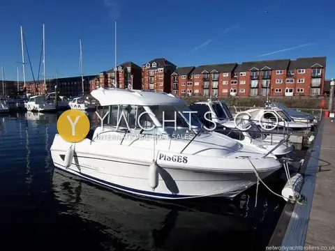 Beneteau Antares 5.80: starboard bow quarter of the white wheelhouse boat Pisces moored on a pontoon among red-brick flats