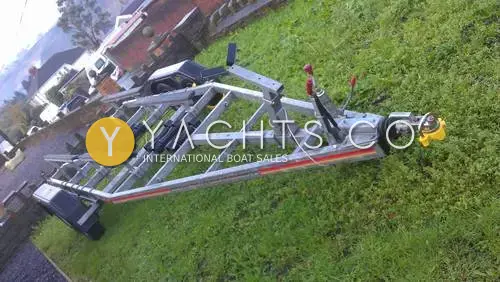 Beneteau Antares 620: galvanised road trailer with roller bunks parked on grass beside a driveway