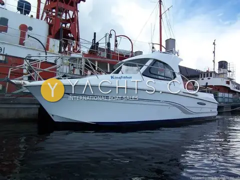 Beneteau Antares 7: port side of the white hull named Kingfisher, moored beside red historic vessels